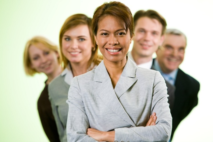 Portrait of successful businesswoman looking at camera with several employees behind
